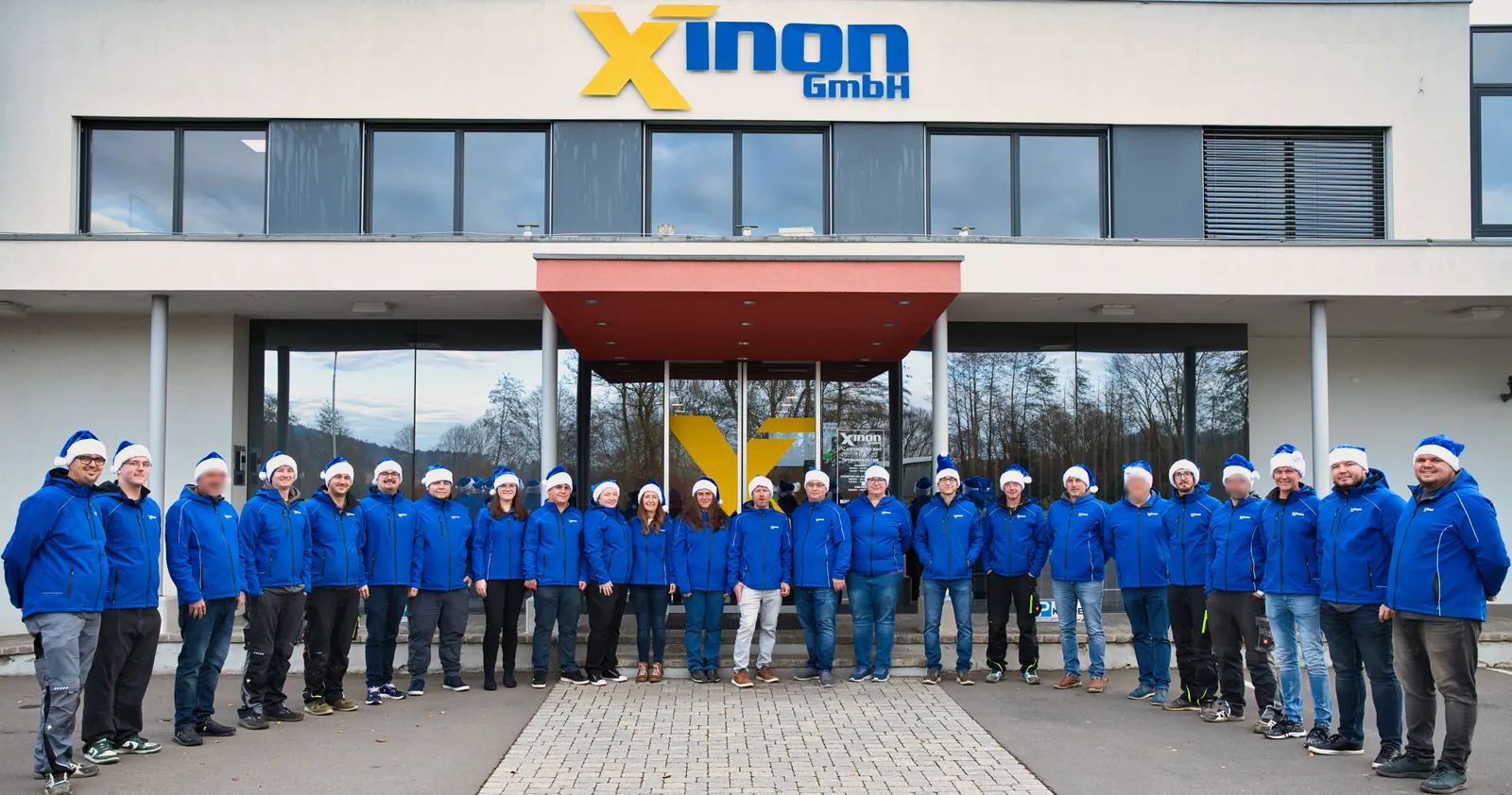 Das XINON Team mit Weihnachtsmützen vor dem Firmengebäude in Studenzen